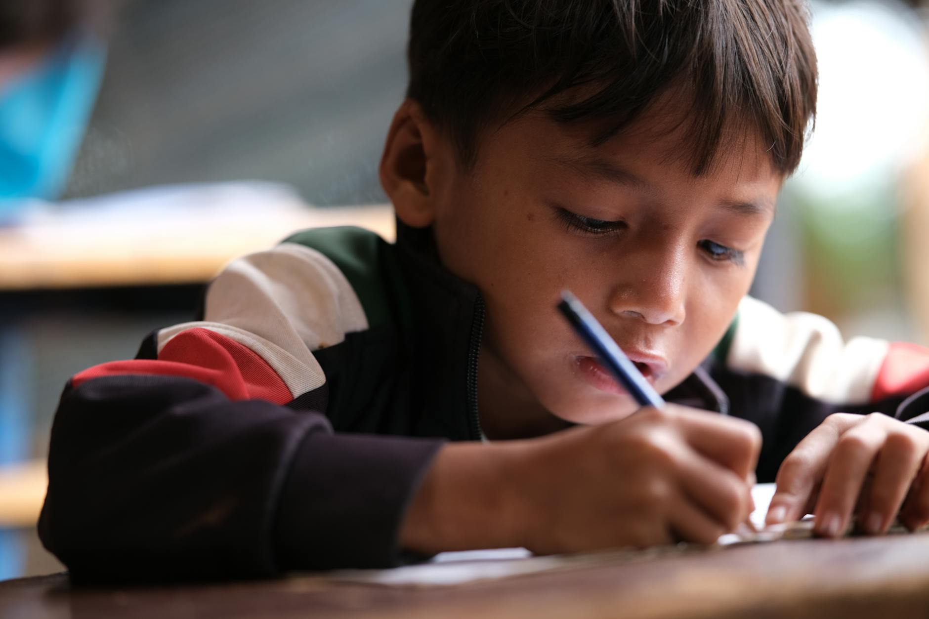 focused young boy writing in classroom